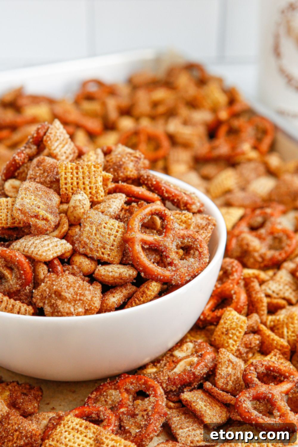 A large tray filled with sweet Churro Chex Mix, alongside a smaller bowl overflowing with the snack, ready to serve.