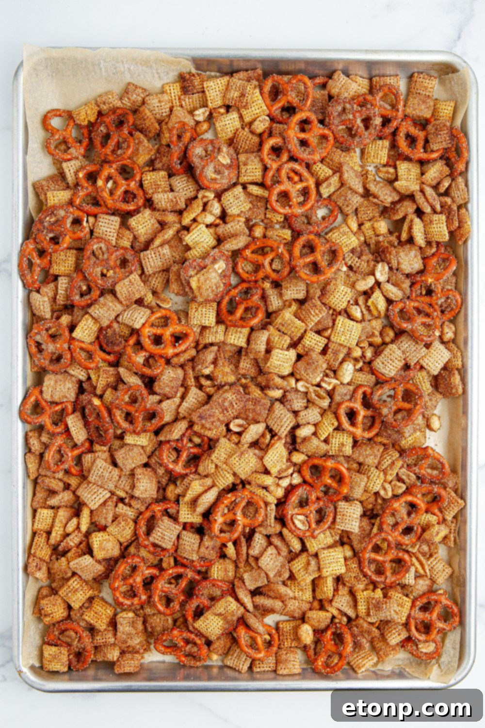 The Churro Chex Mix spread out on a cookie sheet, perfectly coated and ready for baking.