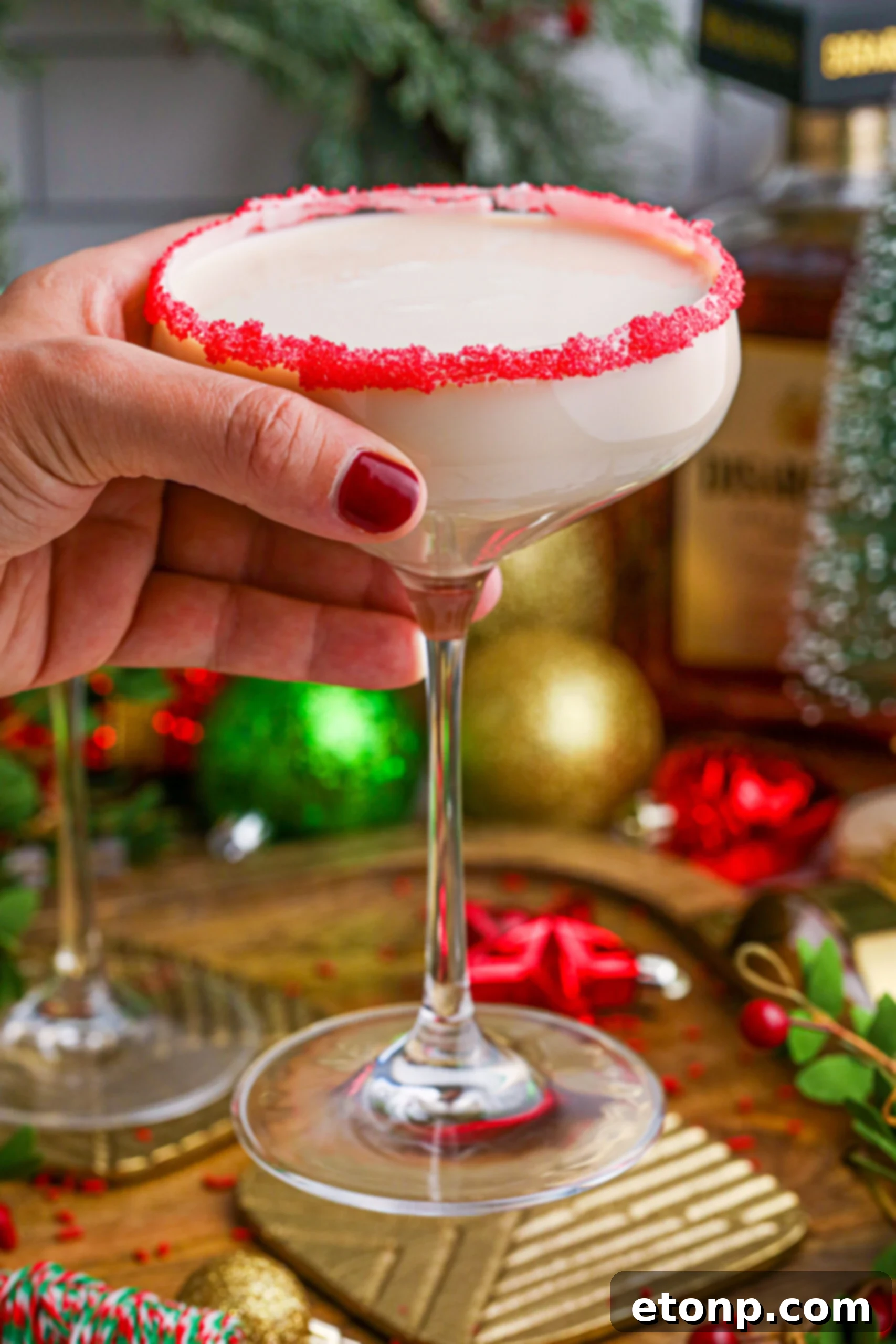 Sugar Cookie Cocktails in a glass with a red sugar rim being held by a hand