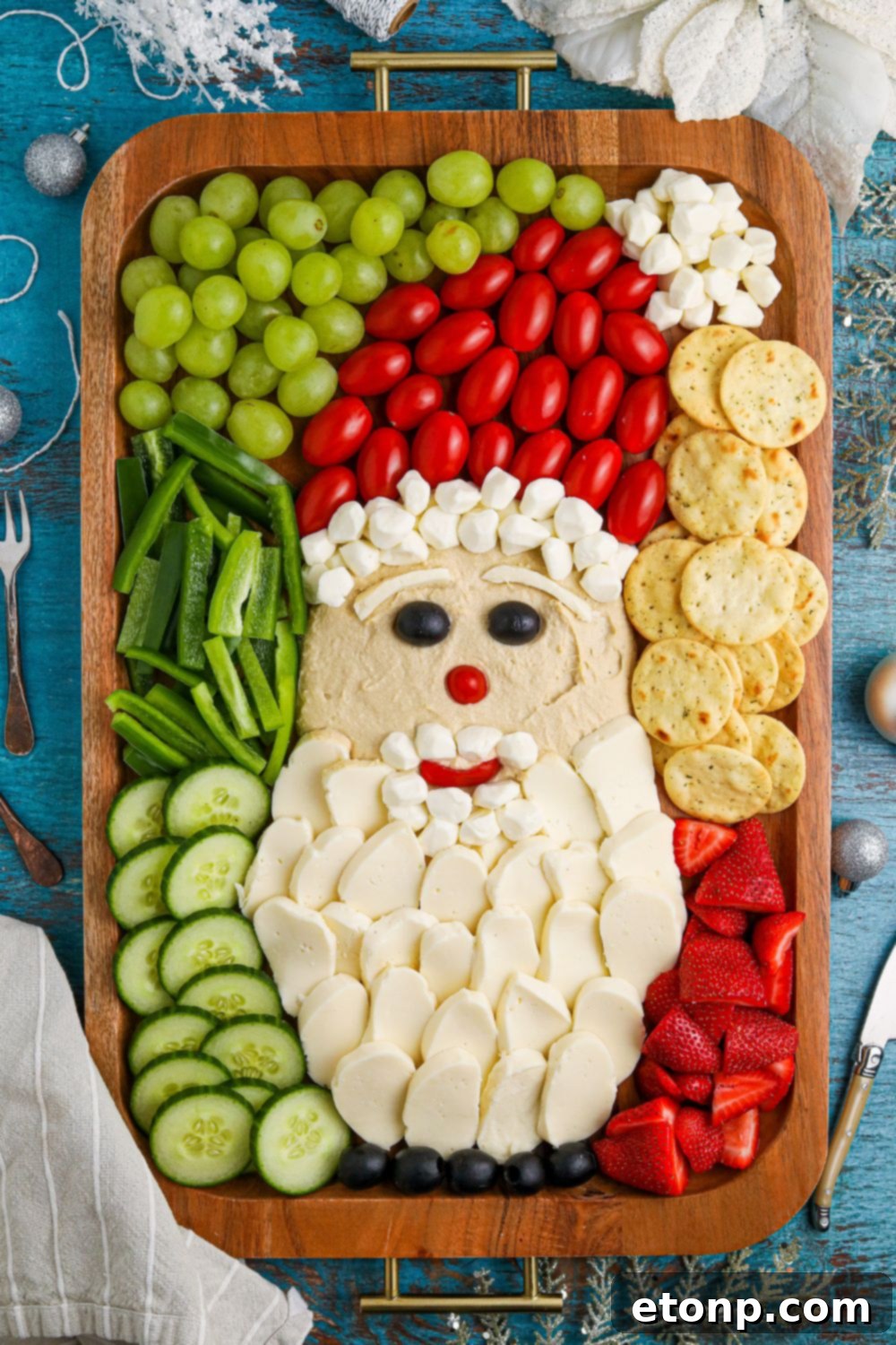A festive Christmas Santa charcuterie board on a rustic wooden table, surrounded by holiday decor.