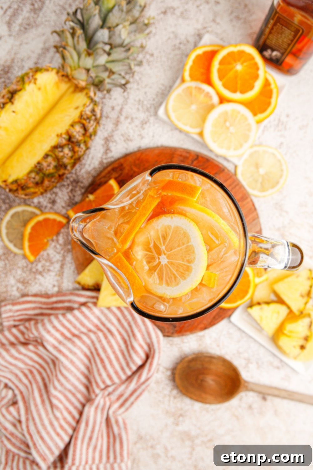 Sweet tea with bourbon in a serving pitcher, surrounded by fresh fruit slices