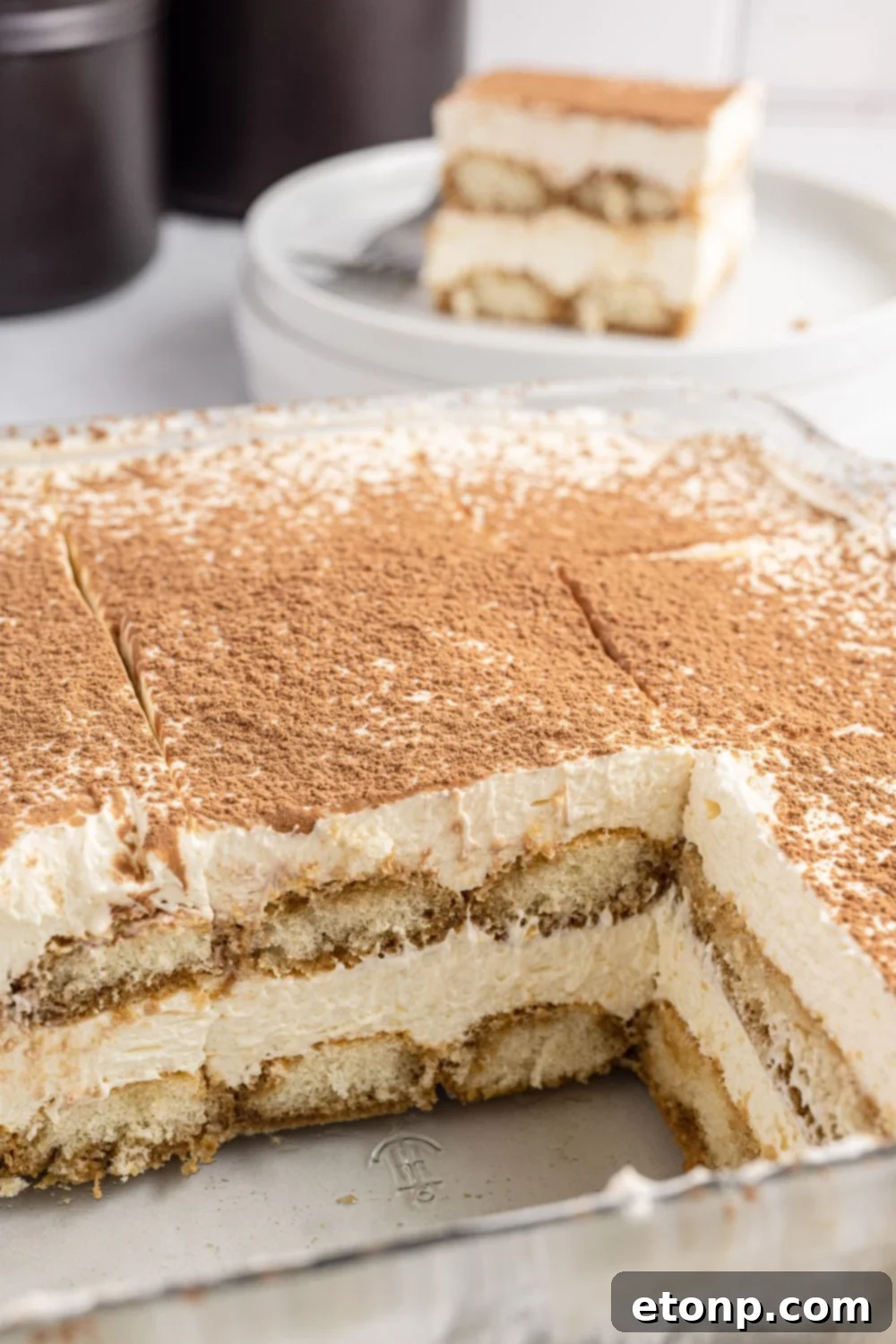 A small, rectangular glass pan of tiramisu, perfectly sized for two or three servings, showcases a delicate dessert.
