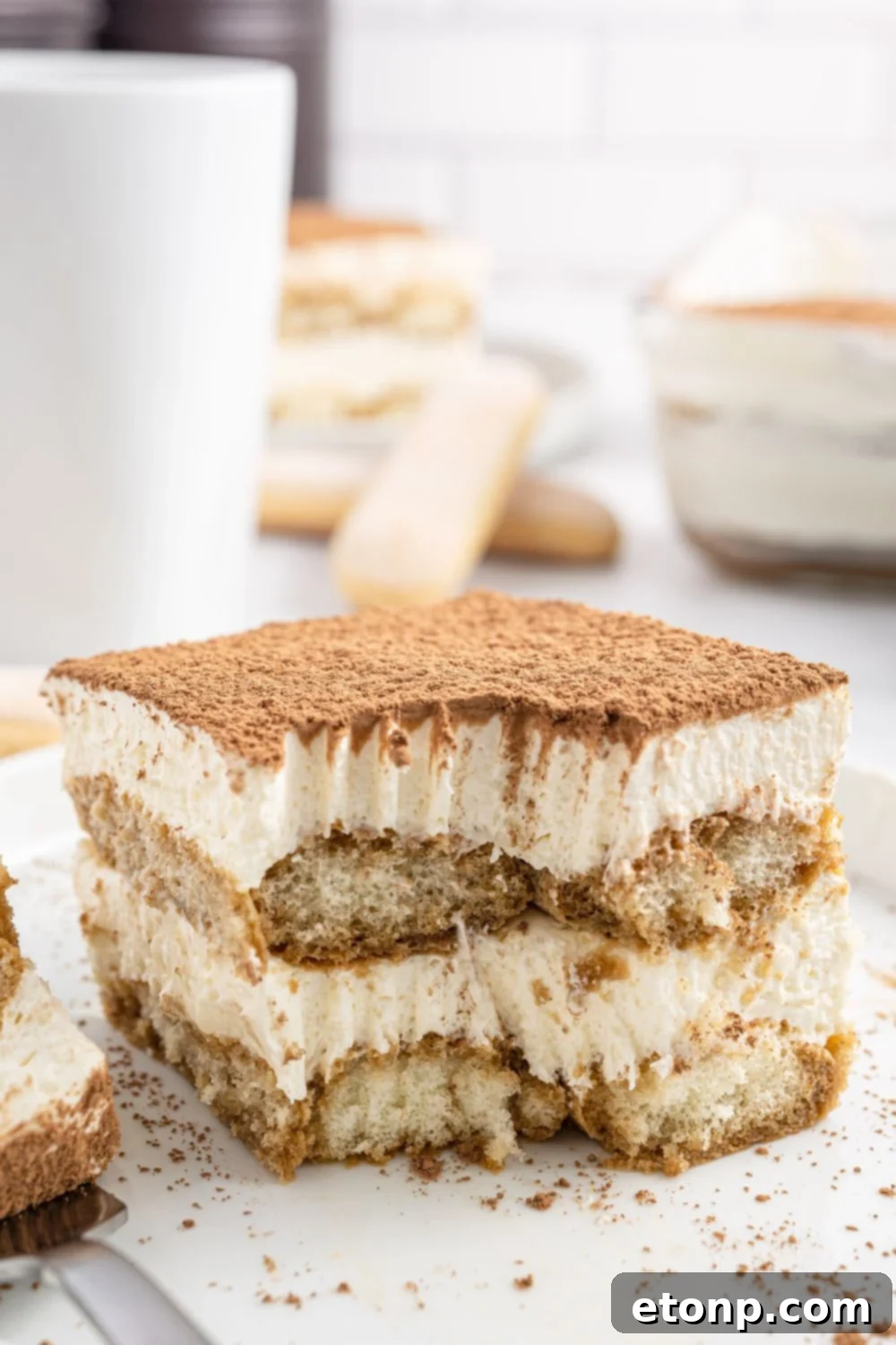 A tempting image of a slice of tiramisu on a plate with a bite already taken, showing the moist layers and creamy filling.