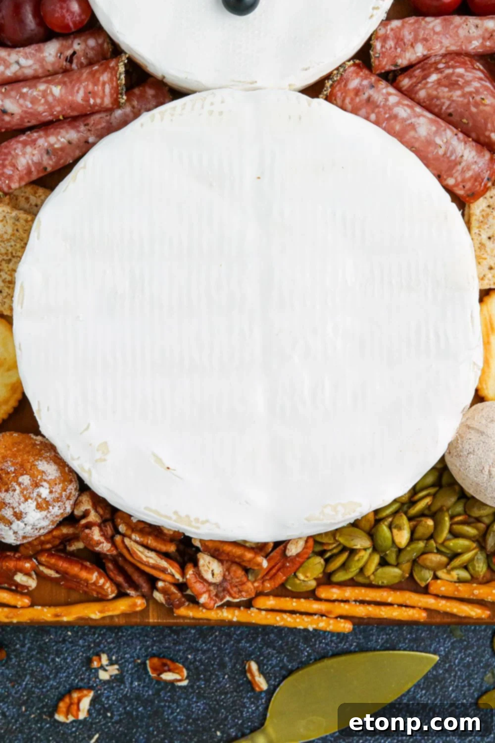 Whimsical Snowman Snack Board 10 Close-up of a brie wheel on a serving tray, forming part of the snowman's body.