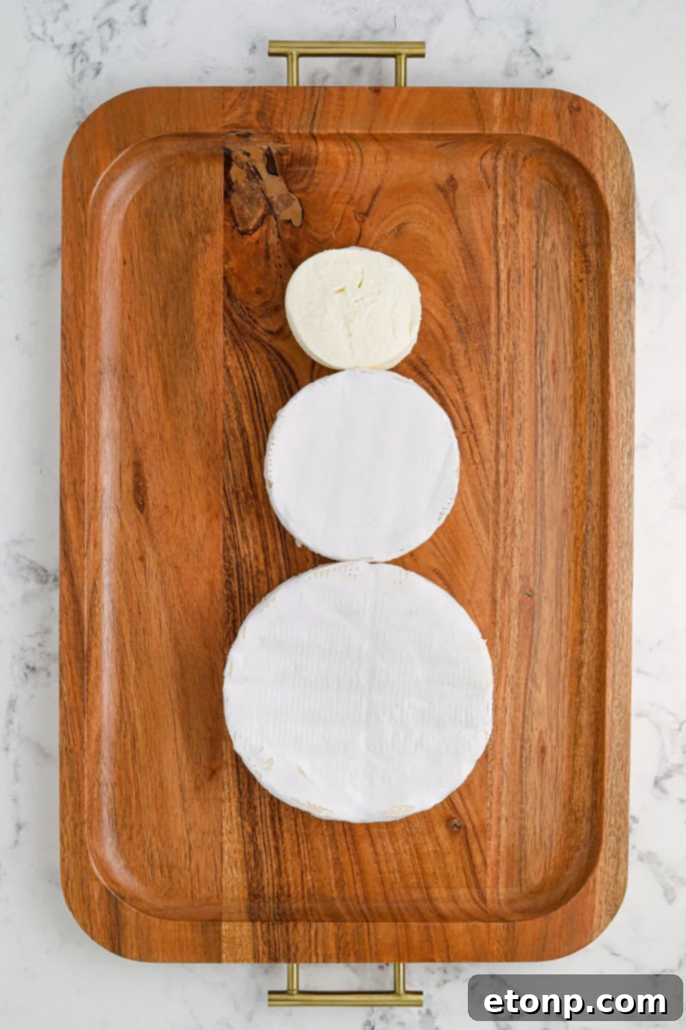 Whimsical Snowman Snack Board 5 Close-up of brie cheese wheels forming the base of a snowman on a platter.