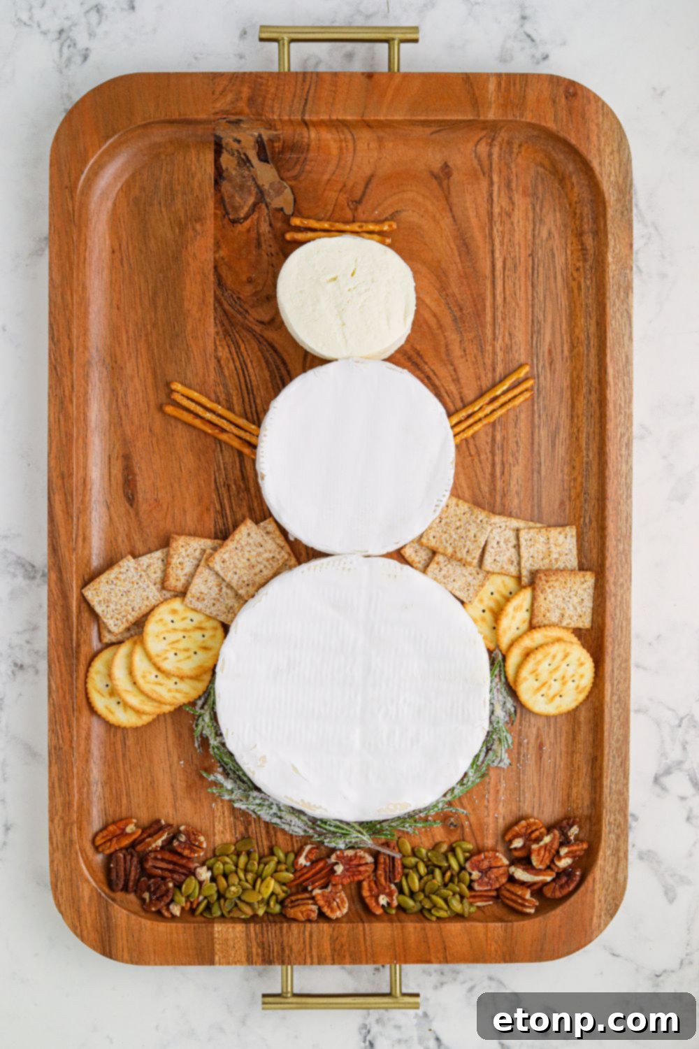 Whimsical Snowman Snack Board 6 Brie cheese wheels arranged to resemble a snowman on a serving tray, ready for decoration.