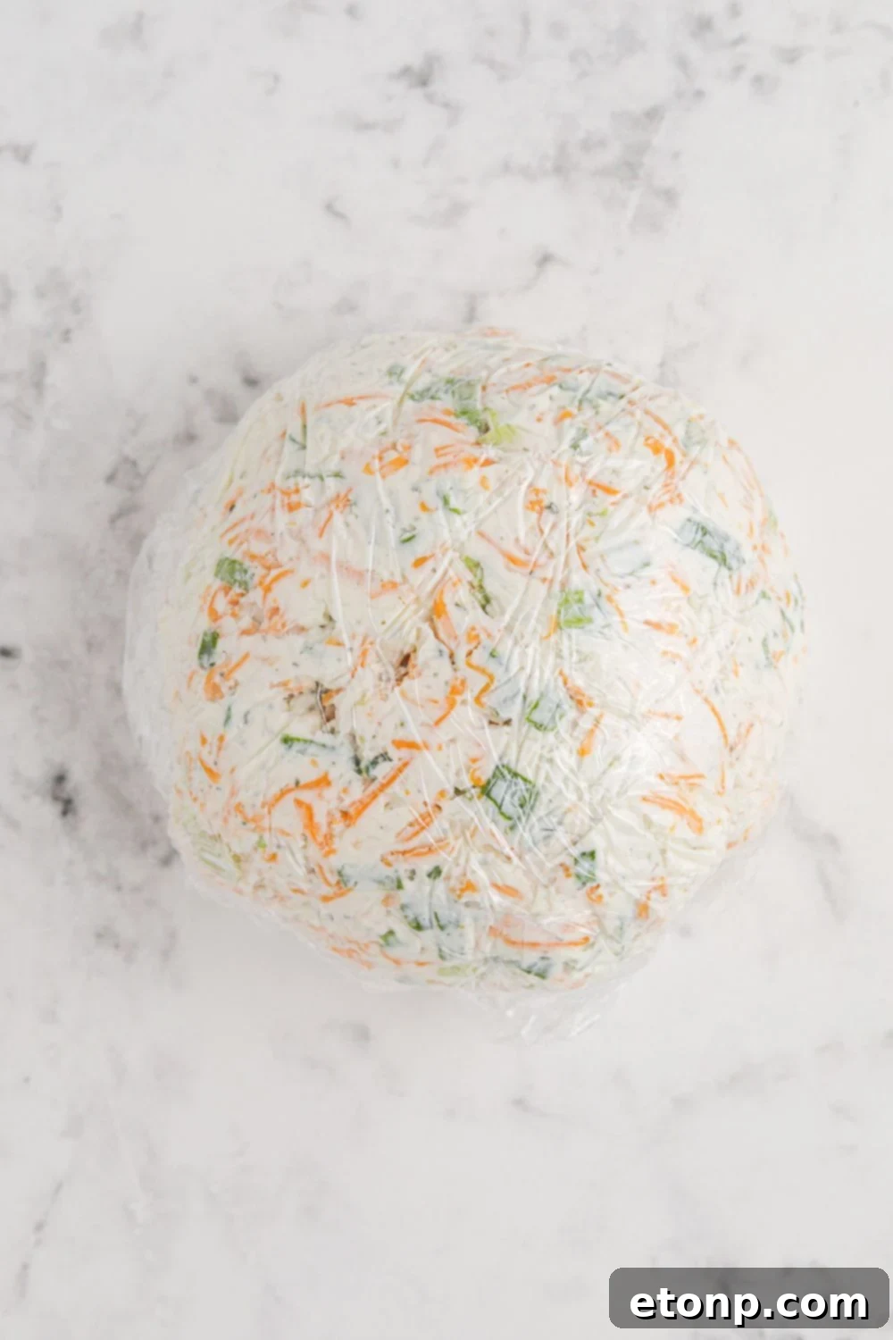 cheese ball wrapped in plastic wrap on table