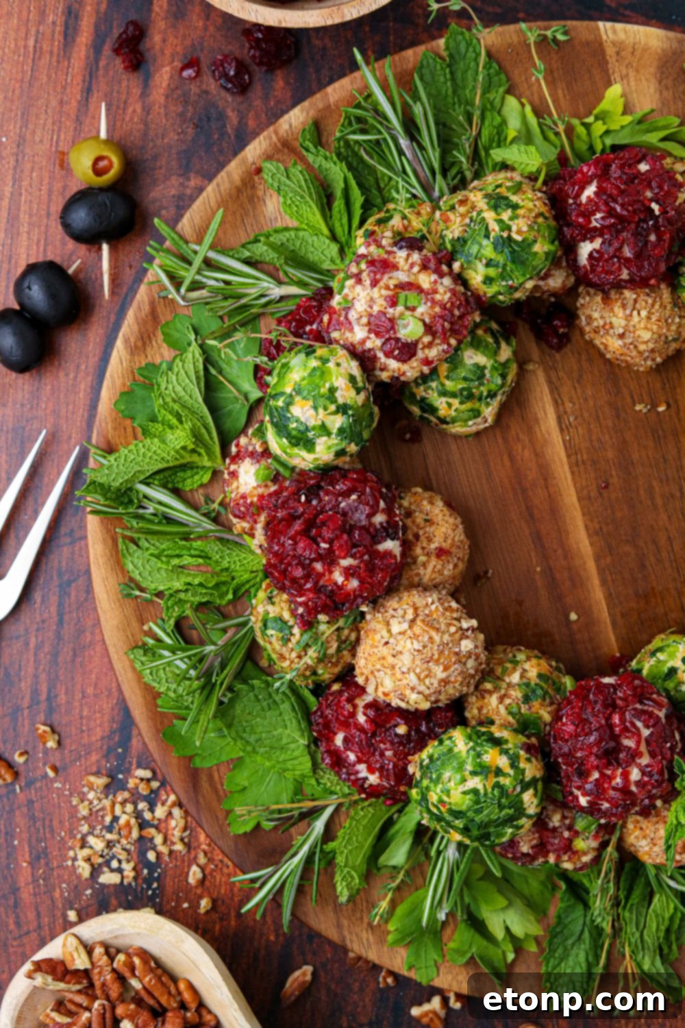 half of a cheese ball wreath in image with food around a wooden table 