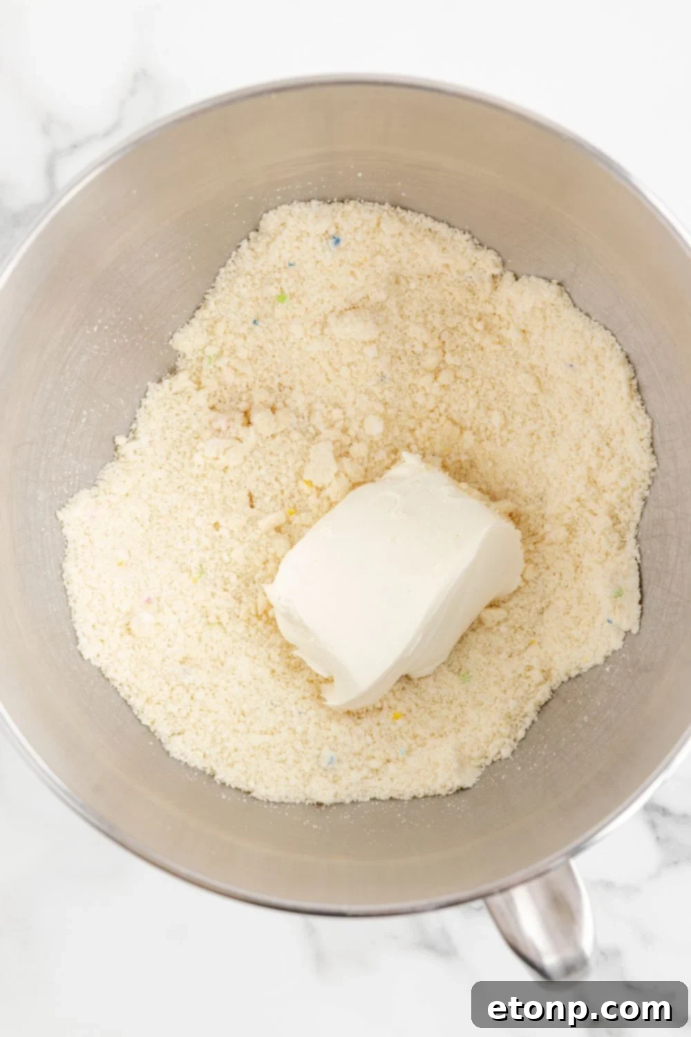 crushed cookies in a bowl with a block of cream cheese on top 