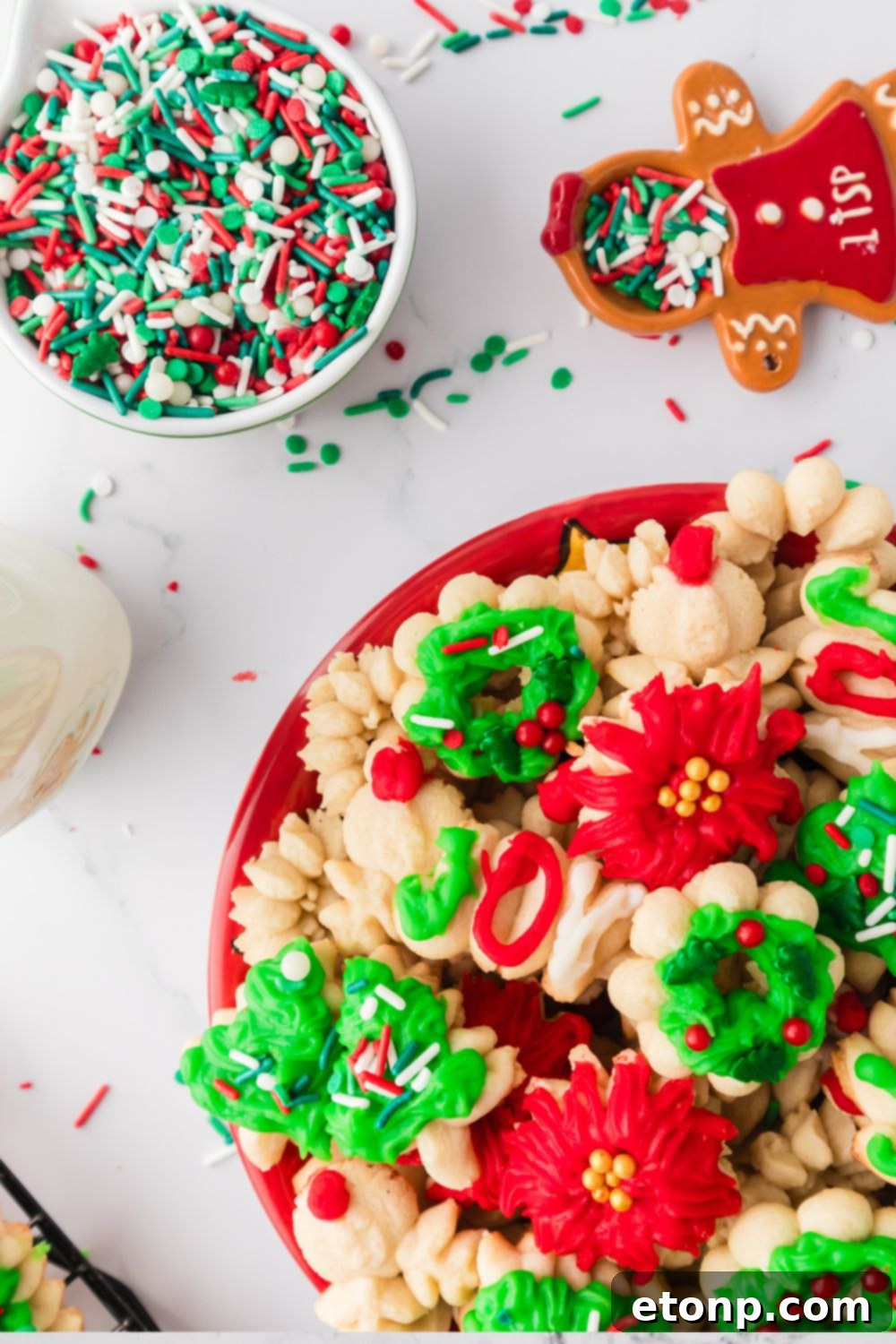 plate loaded with spritz cookies and sprinkles in a bowl to the side
