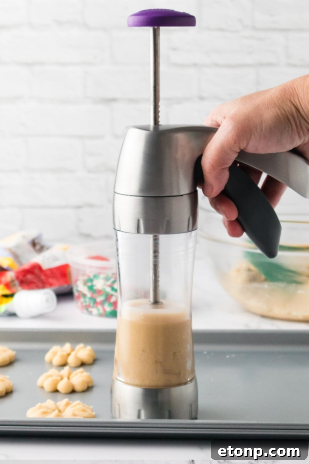 holding cookie press above cookie sheet