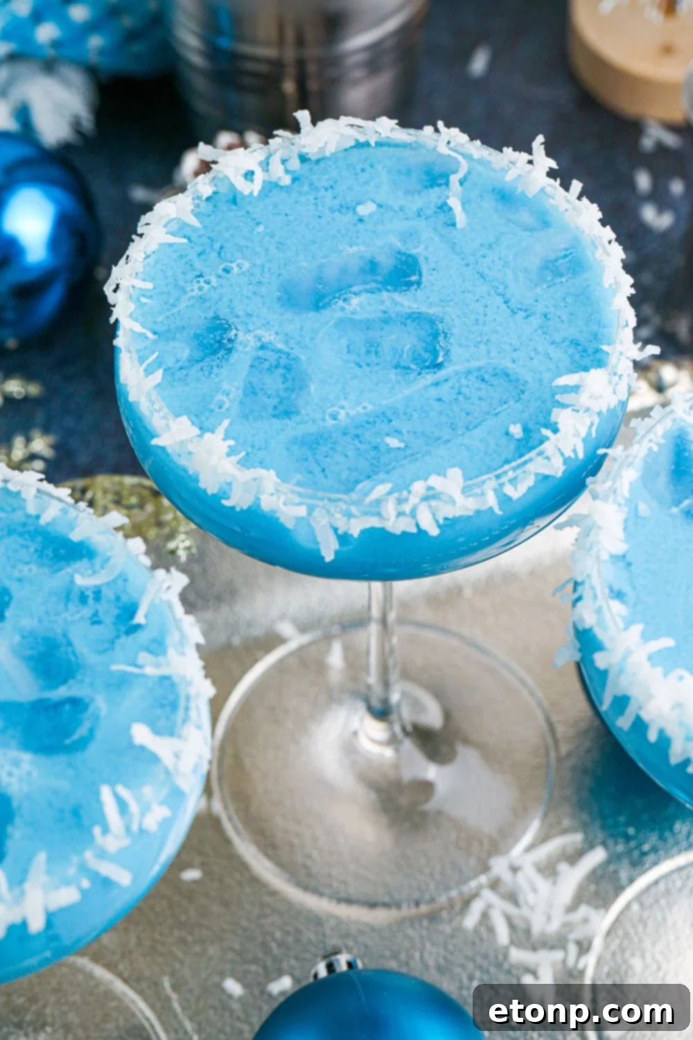 blue colored cocktails in glass with coconut flakes around the rim