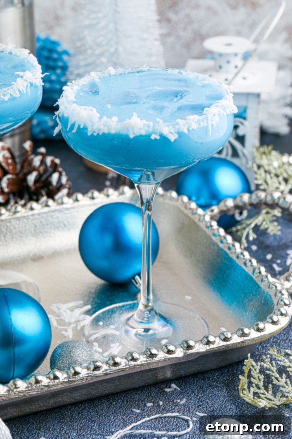 Blue Christmas Cocktail on table with blue Christmas ornaments around it