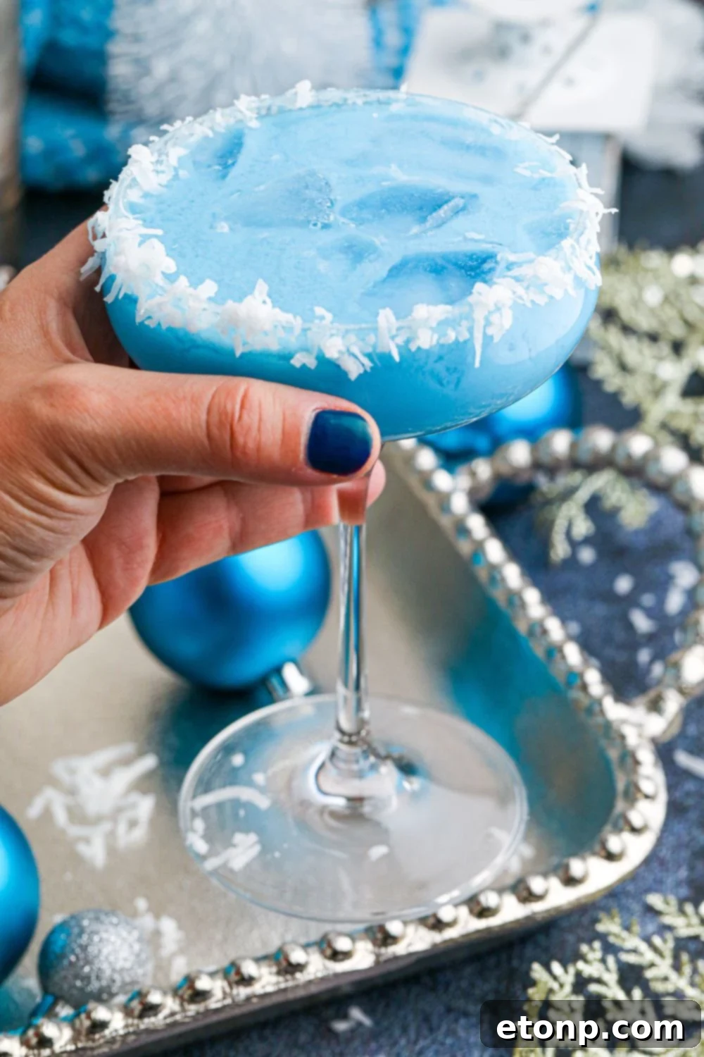 woman holding cocktail glass with blue drink in hand