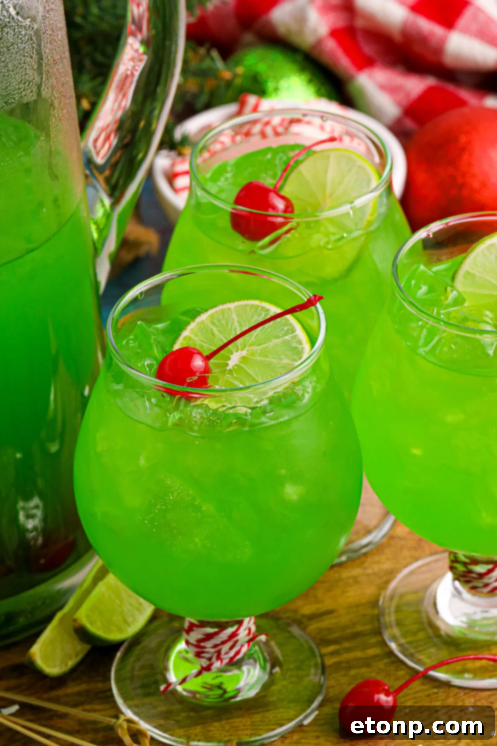 Festive Grinch Punch served in clear glasses with cherries and lime slices, ready for holiday enjoyment.