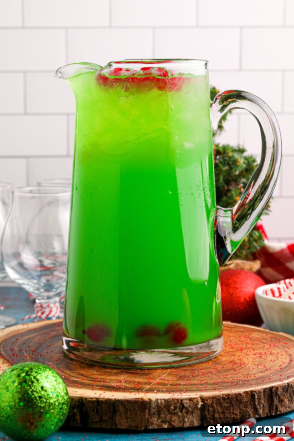A clear pitcher of non-alcoholic punch with cherries and ice floating on top, set on a table for a refreshing holiday drink.