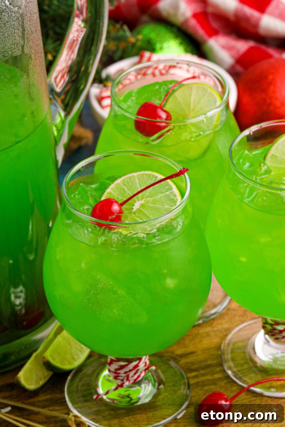 Glasses filled with vibrant lime-flavored punch, garnished with a fresh lime wedge and maraschino cherries on top.