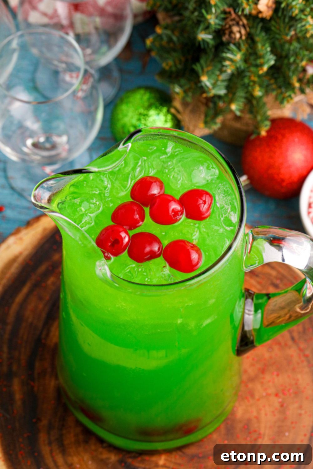 An overhead shot of a large punch bowl filled with green punch, set on a wooden cutting board, ready for a festive occasion.