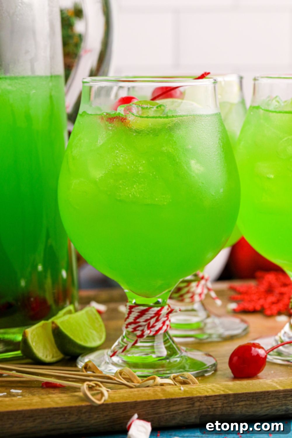 Grinch Punch served in glasses alongside a pitcher of extra punch, ready for a festive gathering.
