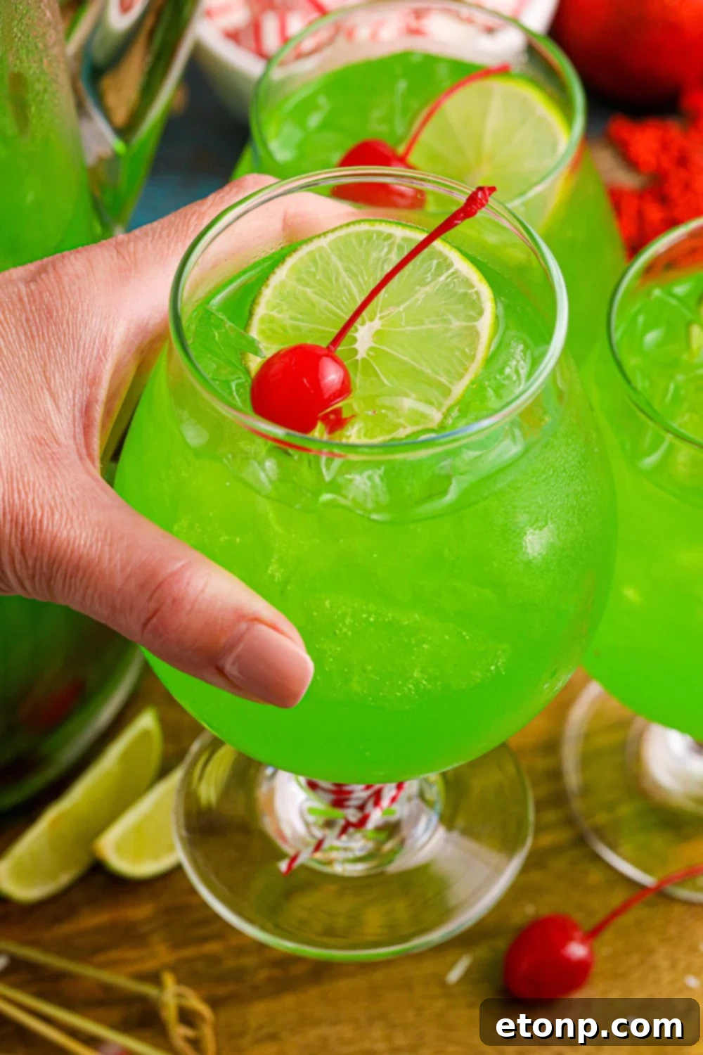 A hand holding a glass of bright green Grinch Punch, perfect for holiday celebrations.