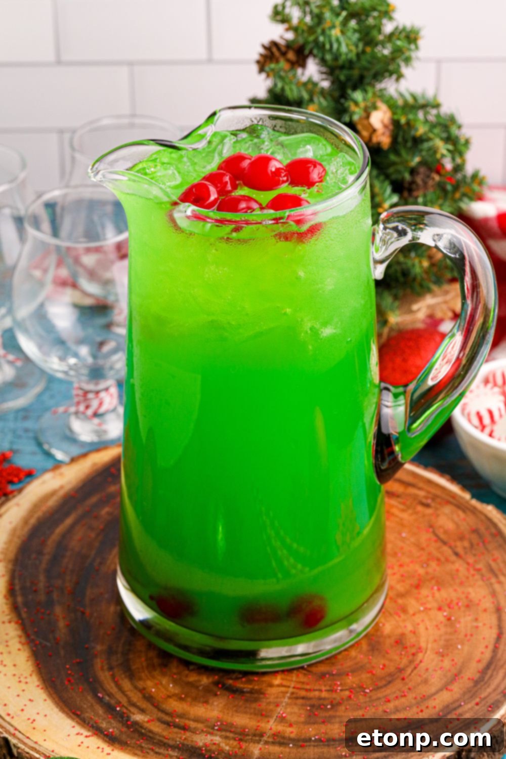 A pitcher of green Grinch Punch on a table, surrounded by subtle Christmas decorations, showcasing a festive holiday drink.