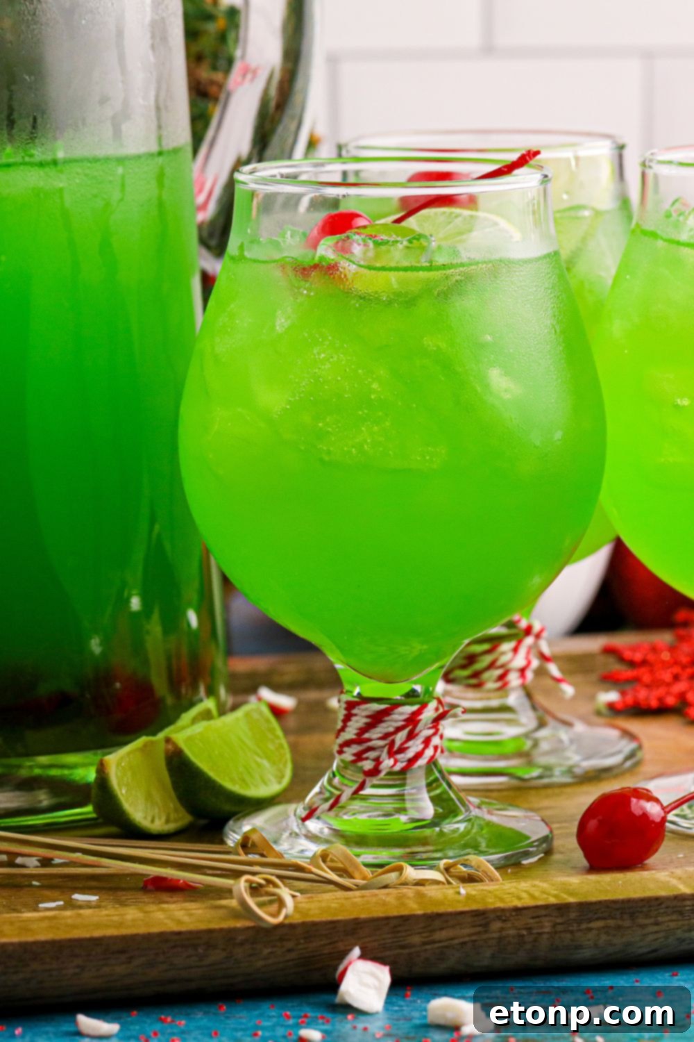 Multiple cocktail glasses filled with a bright green punch, arranged on a wooden cutting board, ready for serving.