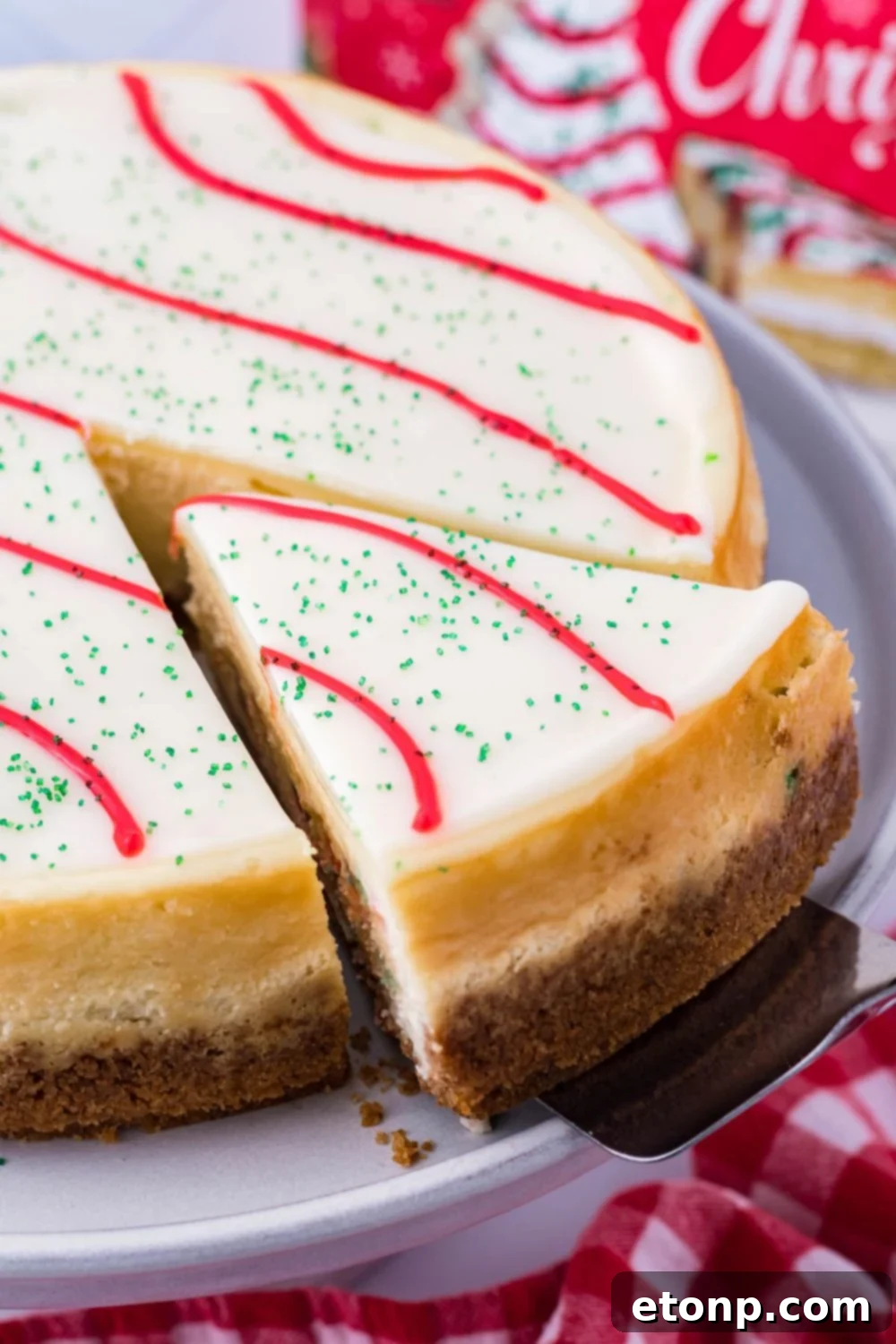A hand using a serving utensil to lift a perfect slice of cheesecake out of a springform pan on a platter, ready to be served.