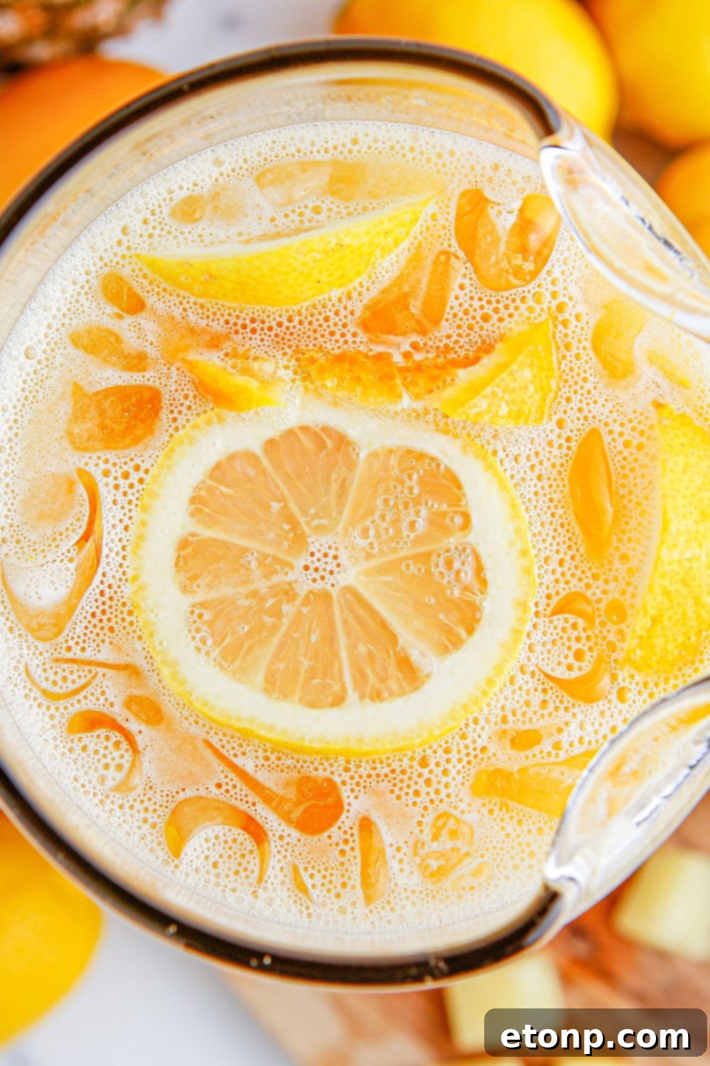 overhead look of party punch in a glass pitcher on table garnishes with sliced fruit