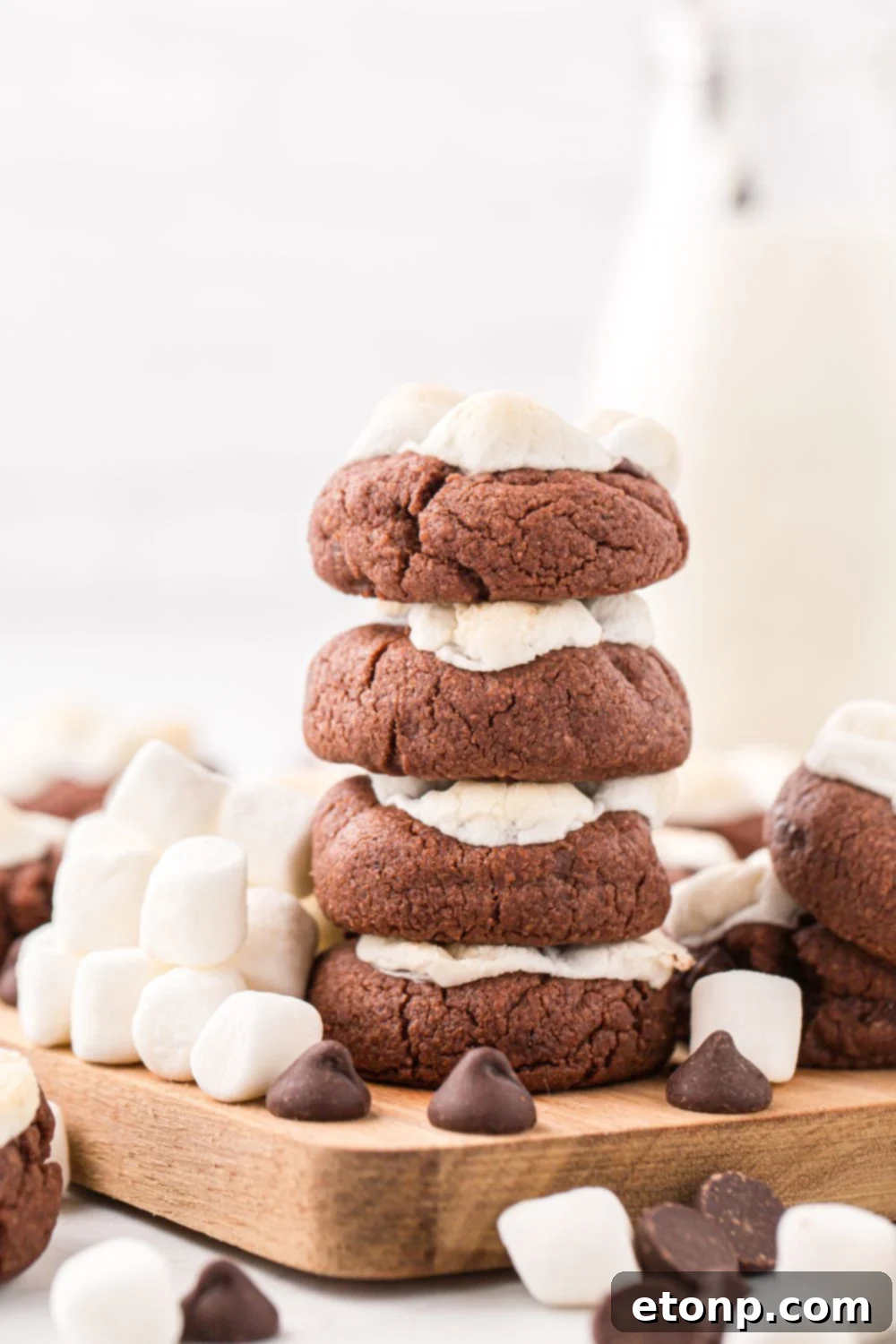 Stack of hot chocolate cookies next to a glass of milk, creating a comforting scene on a table.