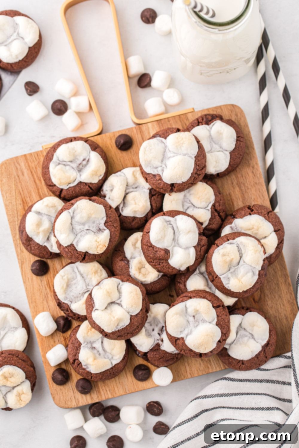 Hot chocolate cookies neatly stacked on a wooden cutting board, showcasing their inviting texture.