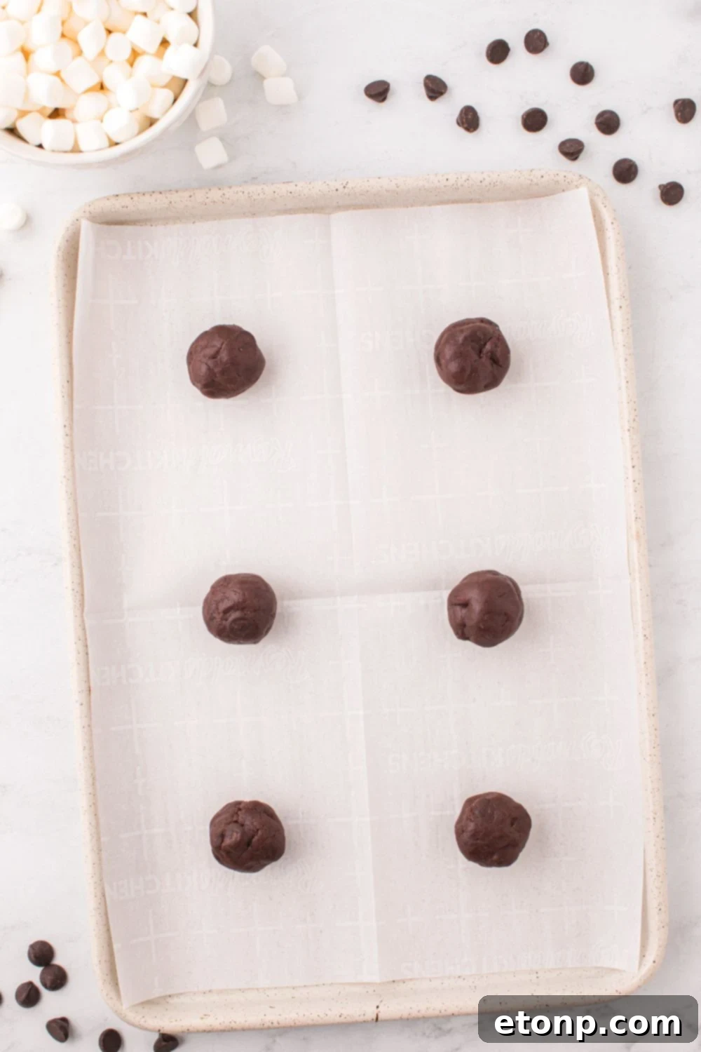 Raw cookie dough balls perfectly scooped and arranged on a baking pan, ready for the oven.
