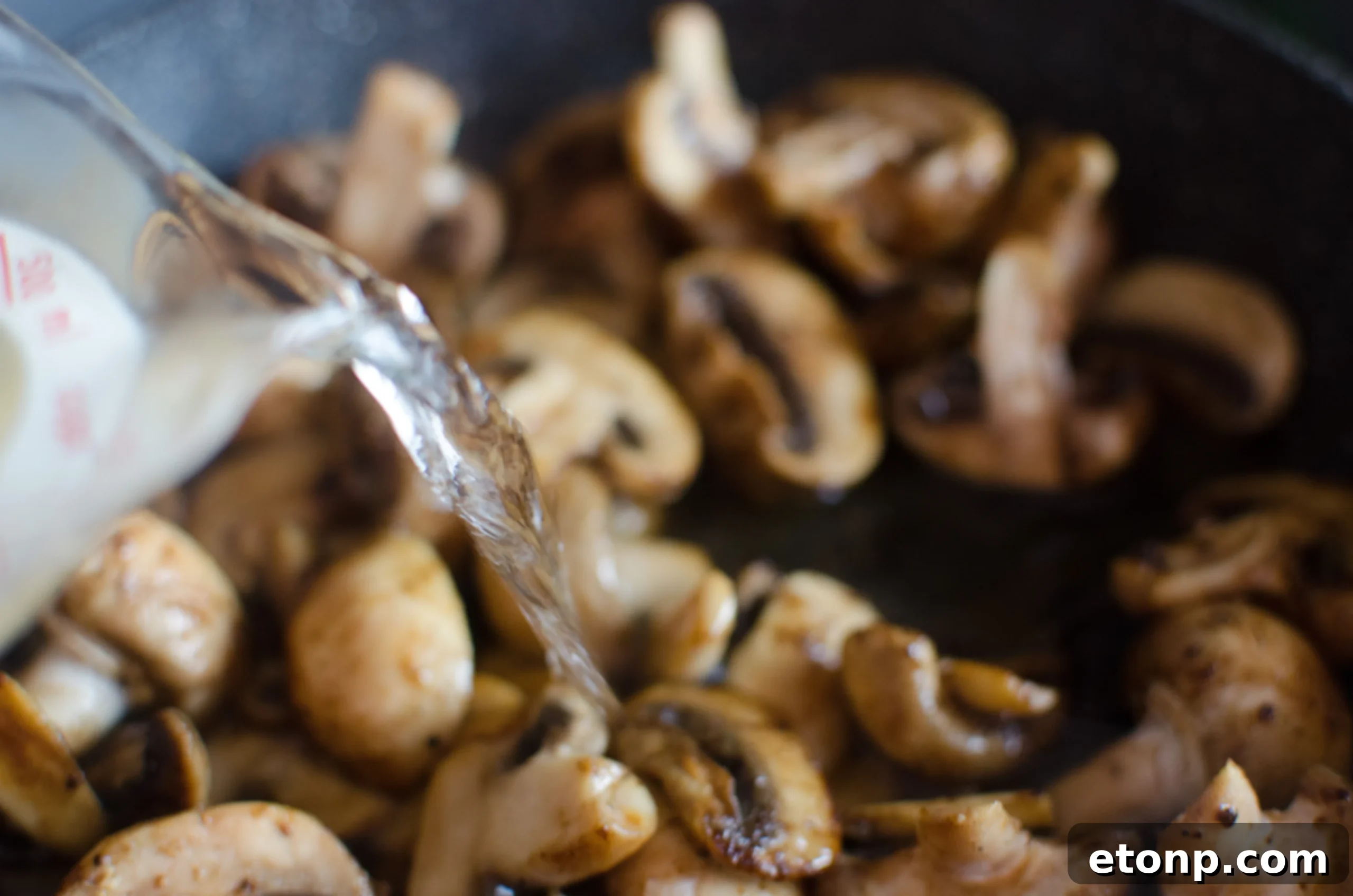 Close-up of golden-brown chicken tenders in a creamy sauce with mushrooms