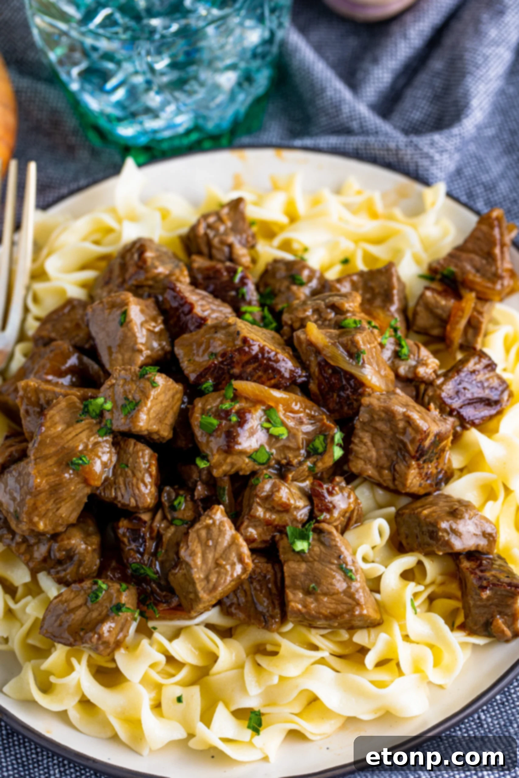 steak bites served over a bed of noodles on a plate