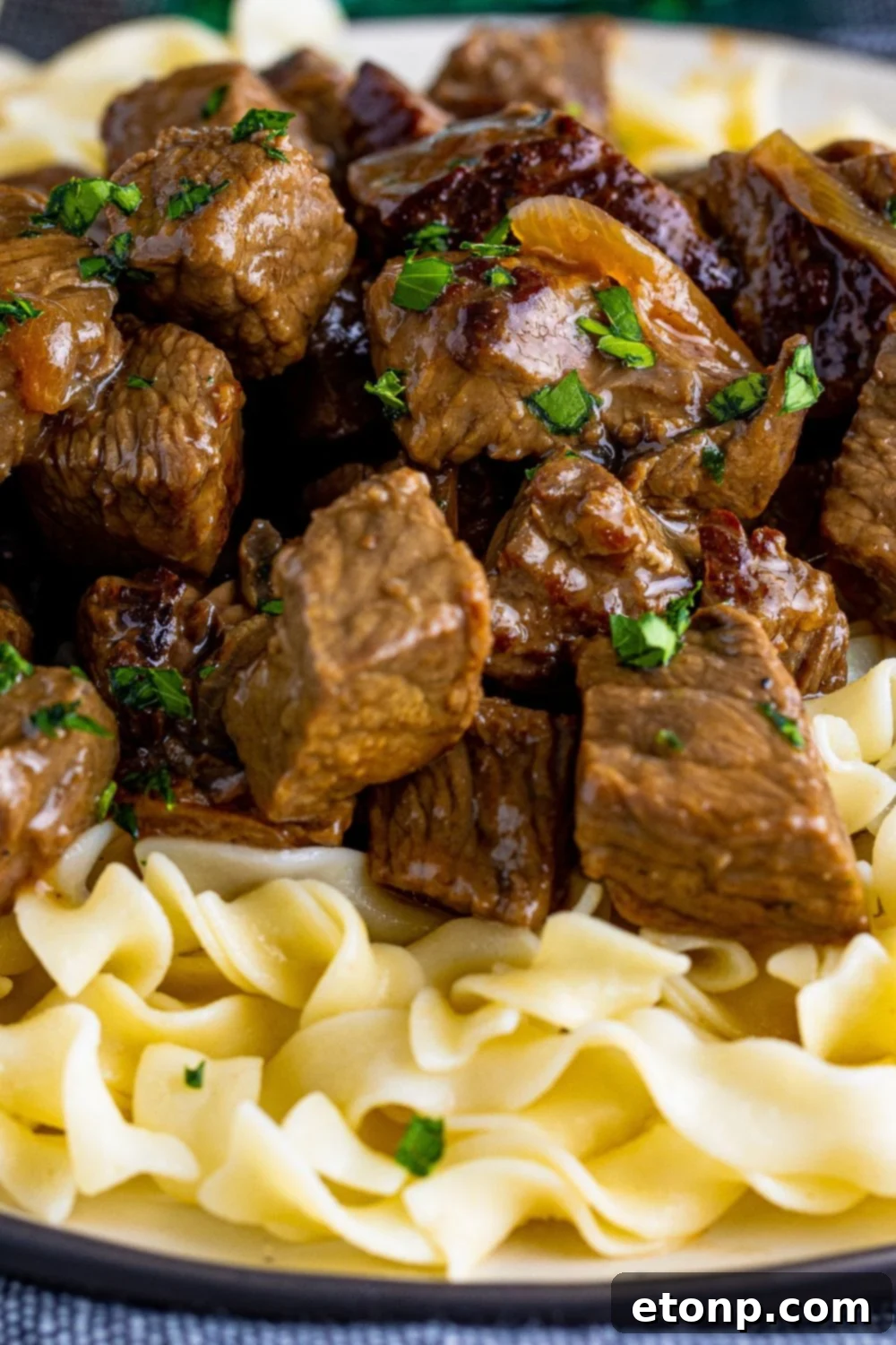 close up view of steak bites on plate with egg noodles under it 