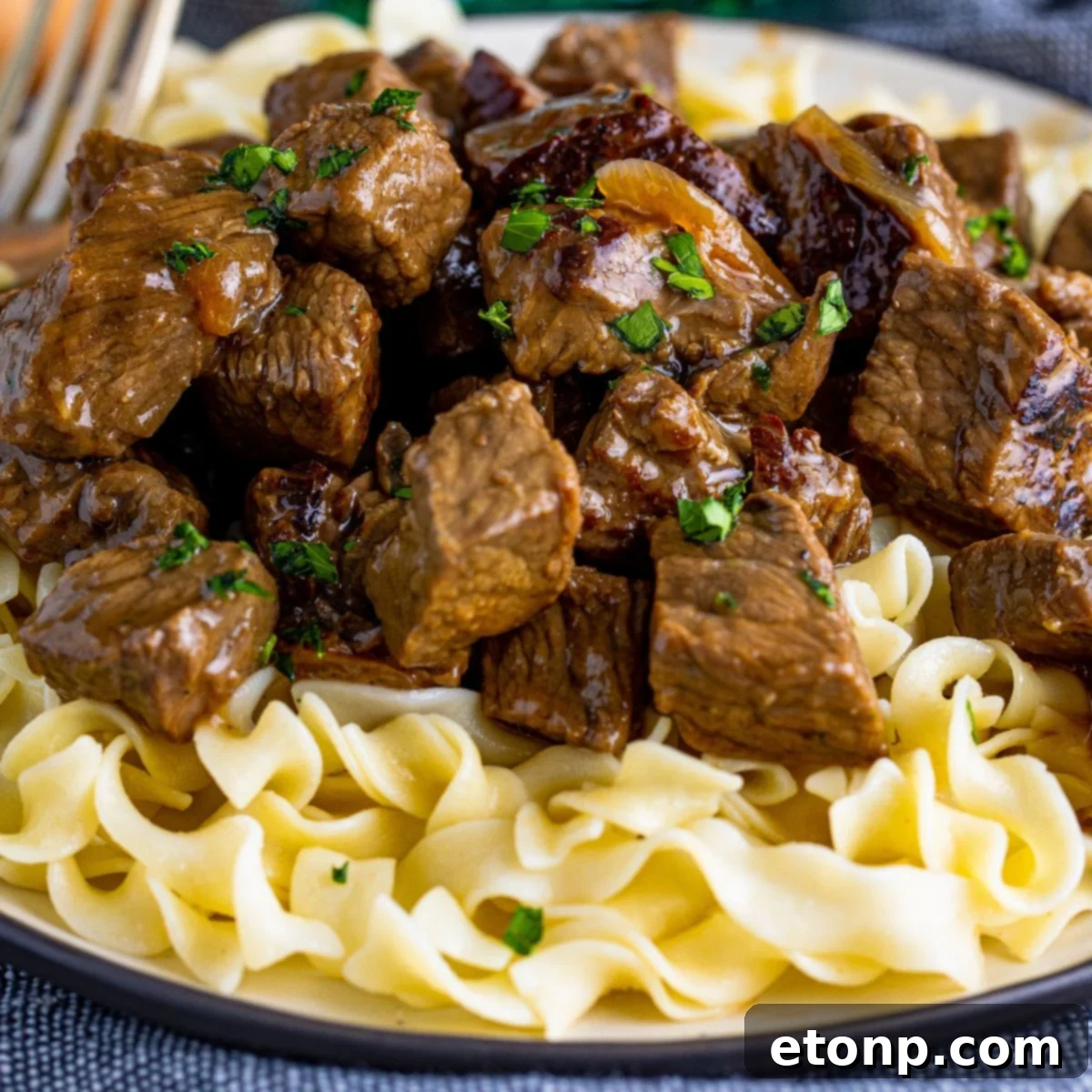 steak bites served over a bed on noodles on a plate