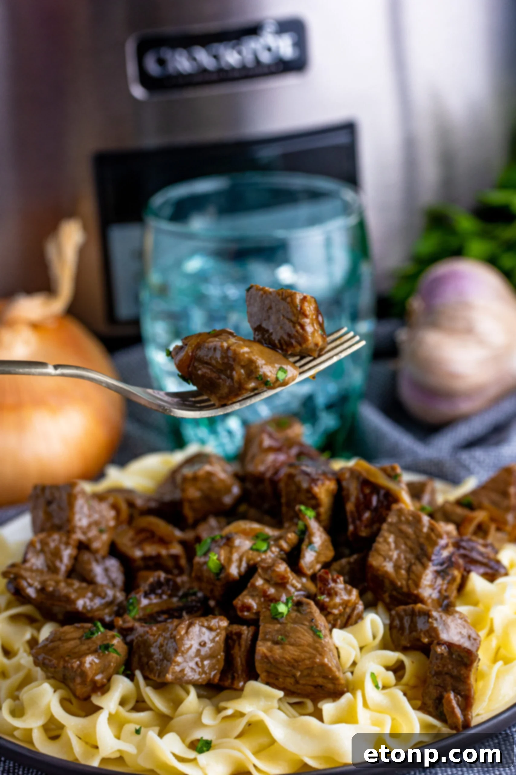 fork with steak bites on it and a crockpot behind it in image