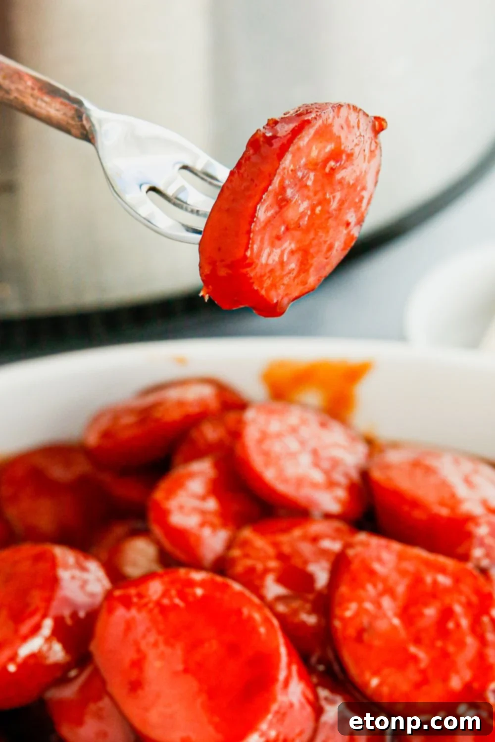 A large bowl filled to the brim with glossy, saucy kielbasa bites, perfect for sharing at a gathering.