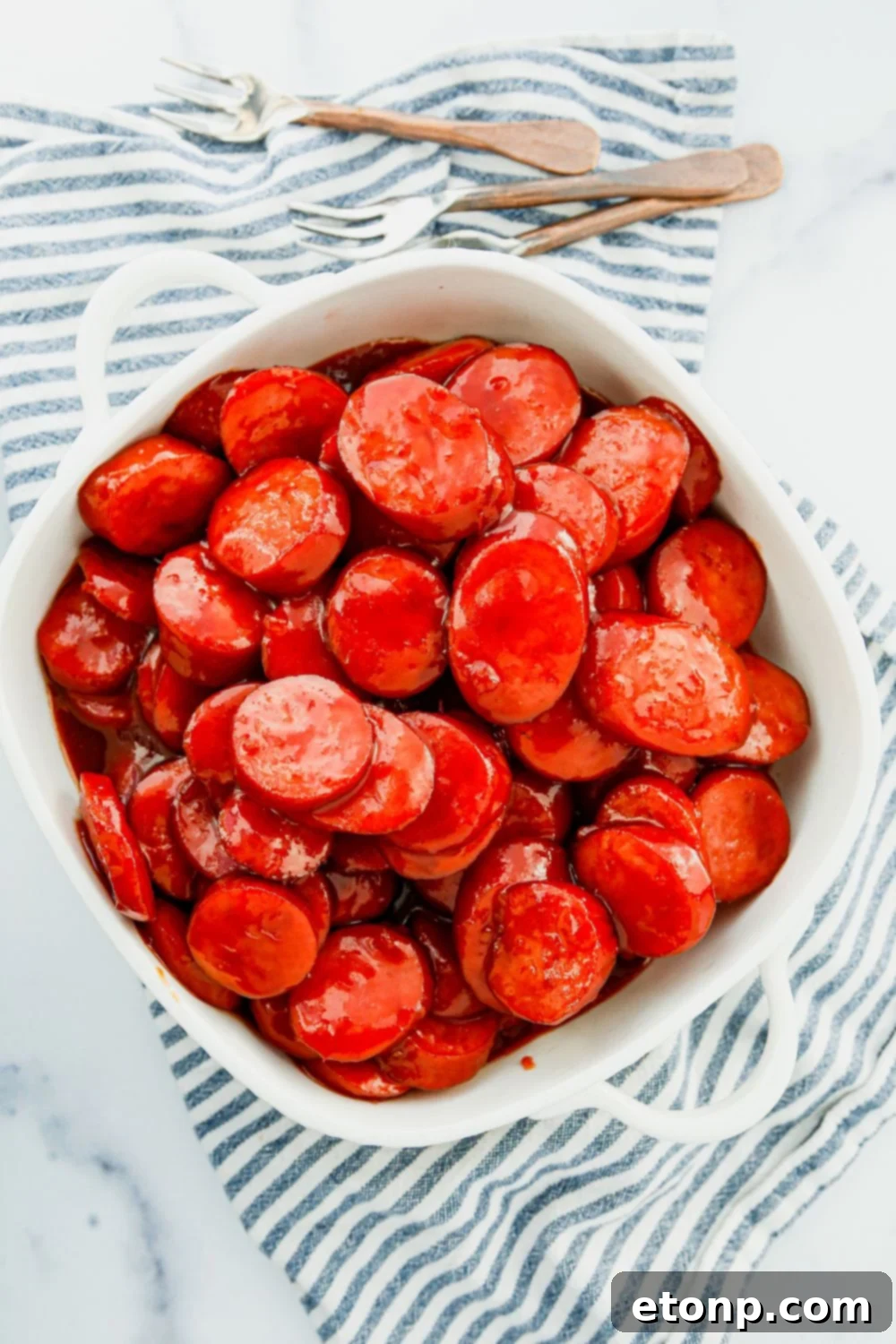 Succulent pieces of Polish sausage swimming in a rich, glossy sauce in a bowl, a close-up of the delicious appetizer.
