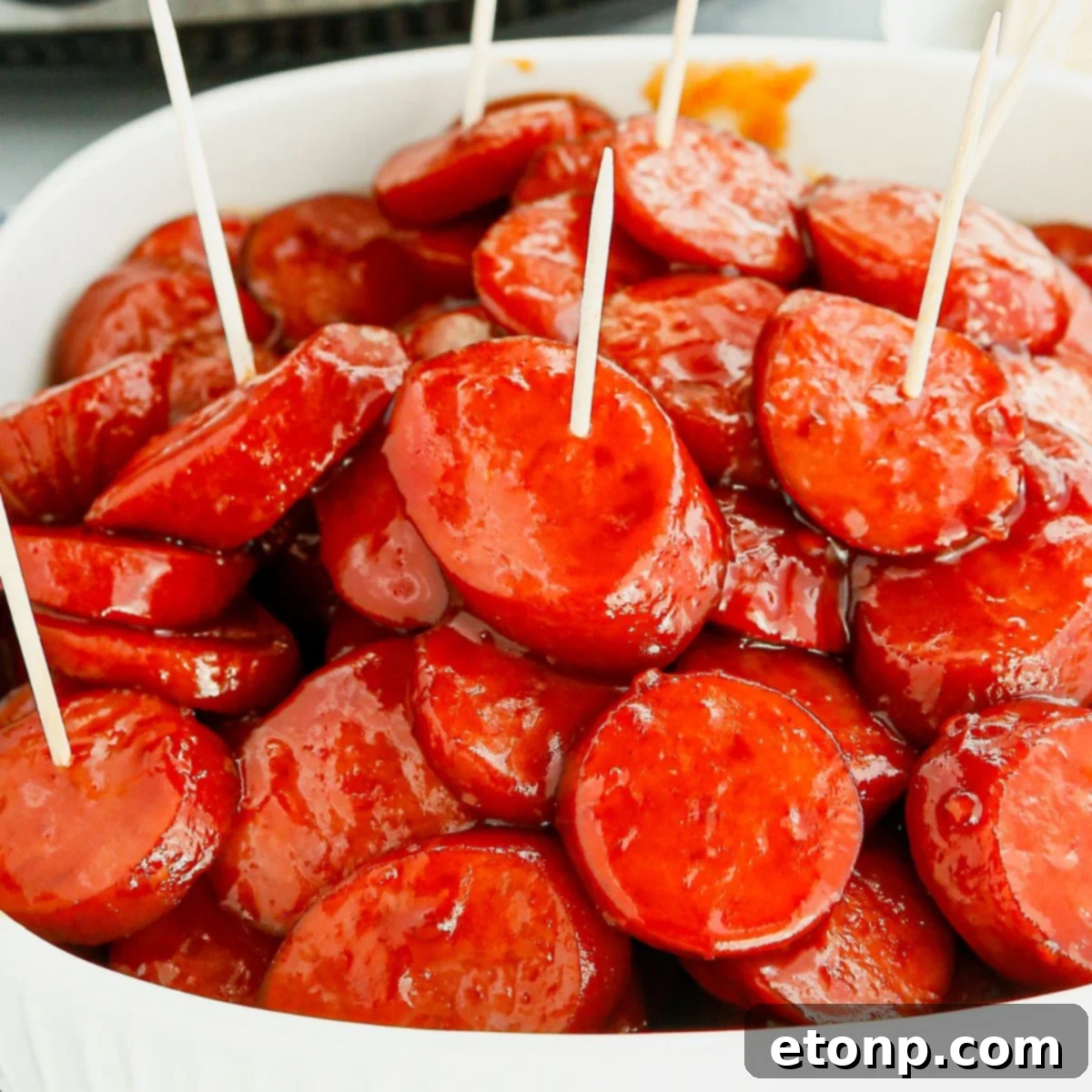 Crockpot Kielbasa Bites glistening in a pan on a rustic wooden table, ready to be devoured.