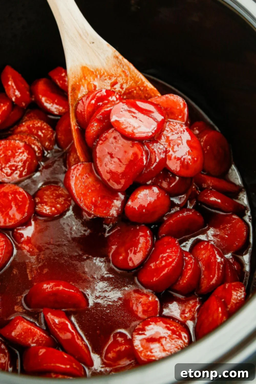 Succulent kielbasa bites simmering in a rich, glossy sauce inside a slow cooker, radiating warmth and flavor.