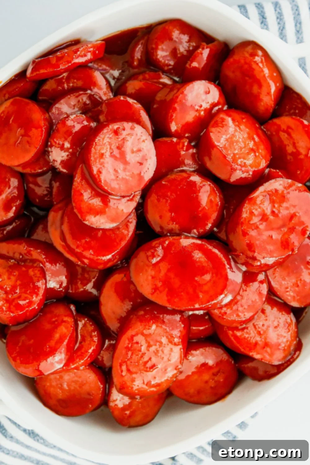 A beautifully plated dish of generously sauced kielbasa bites on a table, garnished and ready for a special occasion.