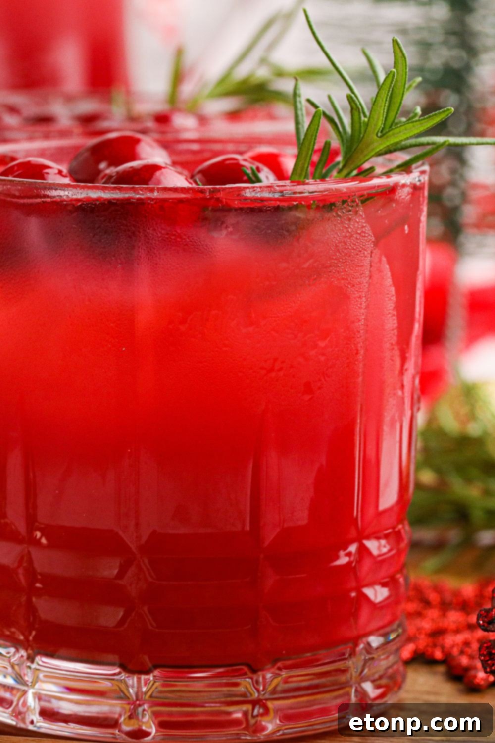 A refreshing side view of cranberry orange punch in a clear glass, showing its vibrant color and festive garnish.