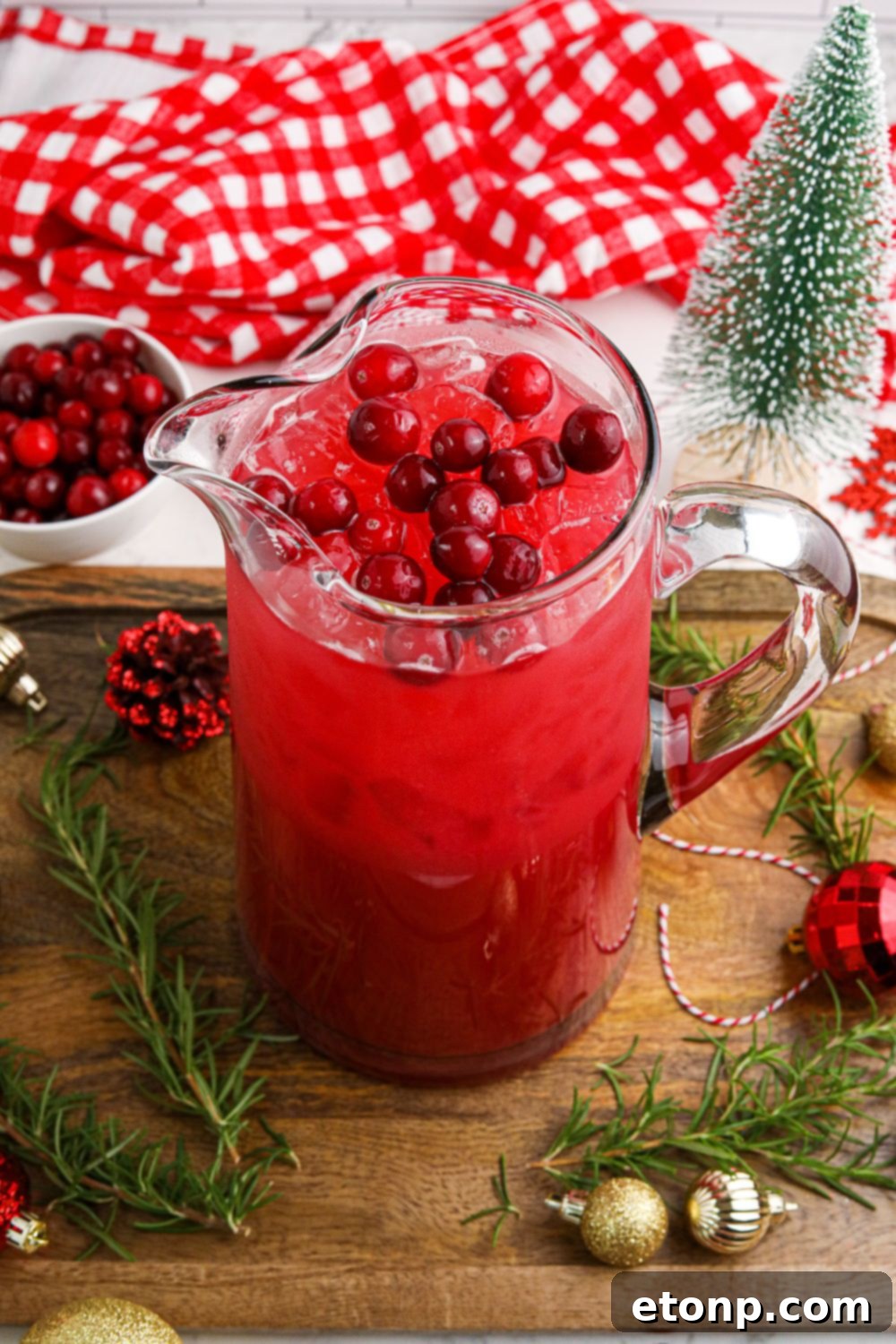 A pitcher of Mistletoe Punch on a festive table, surrounded by charming Christmas decorations, setting a warm holiday ambiance.