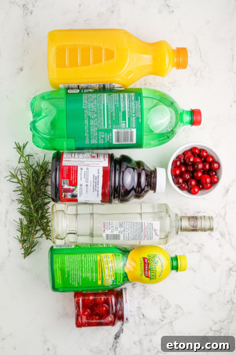 A festive arrangement of fresh cranberries, rosemary sprigs, oranges, and a bottle of vodka, showcasing the key ingredients for the Christmas cocktail.