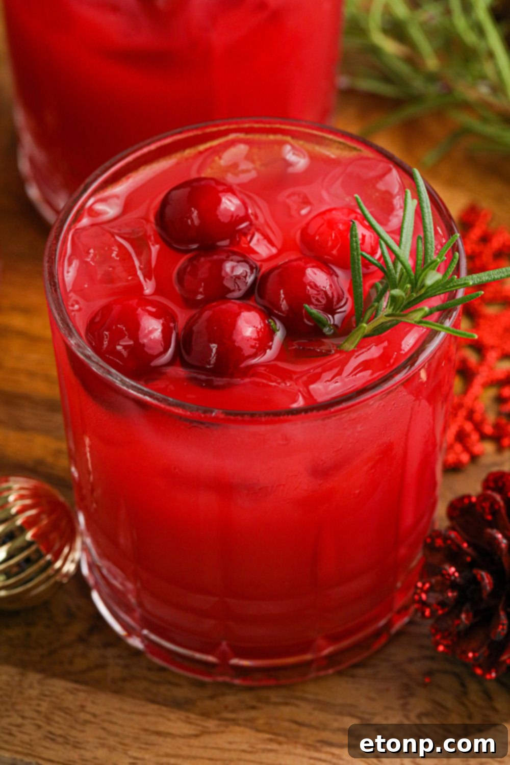 Several glasses of vibrant red Mistletoe Punch arranged on a wooden table, ready for a festive gathering.