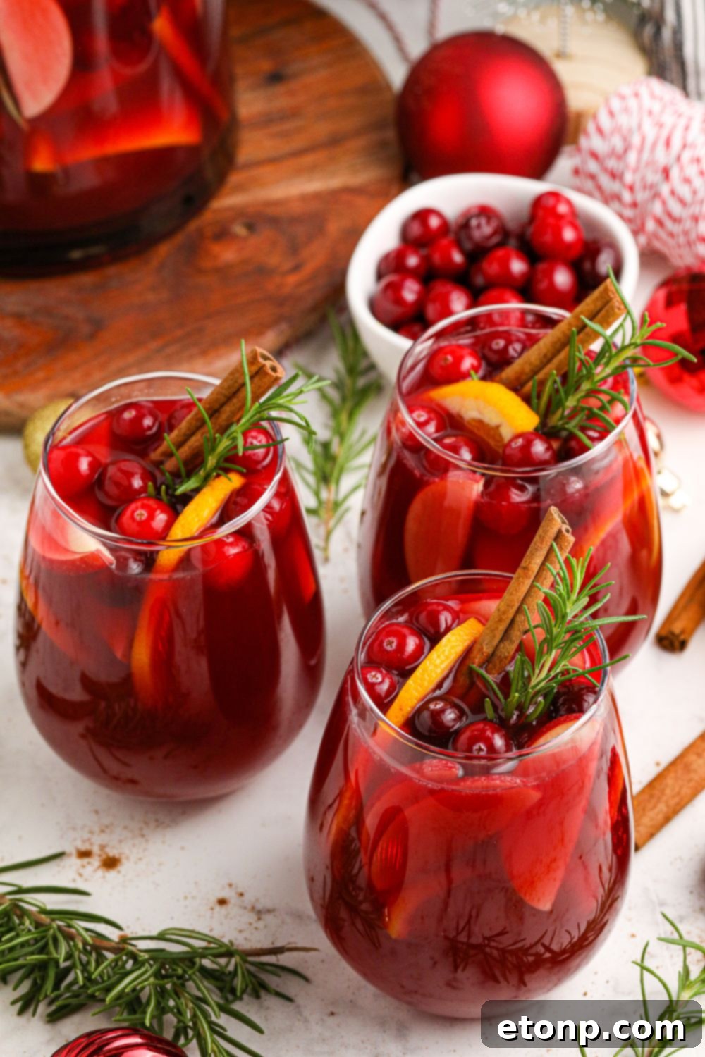 christmas sangria in glasses sitting on tables with ornaments around it 