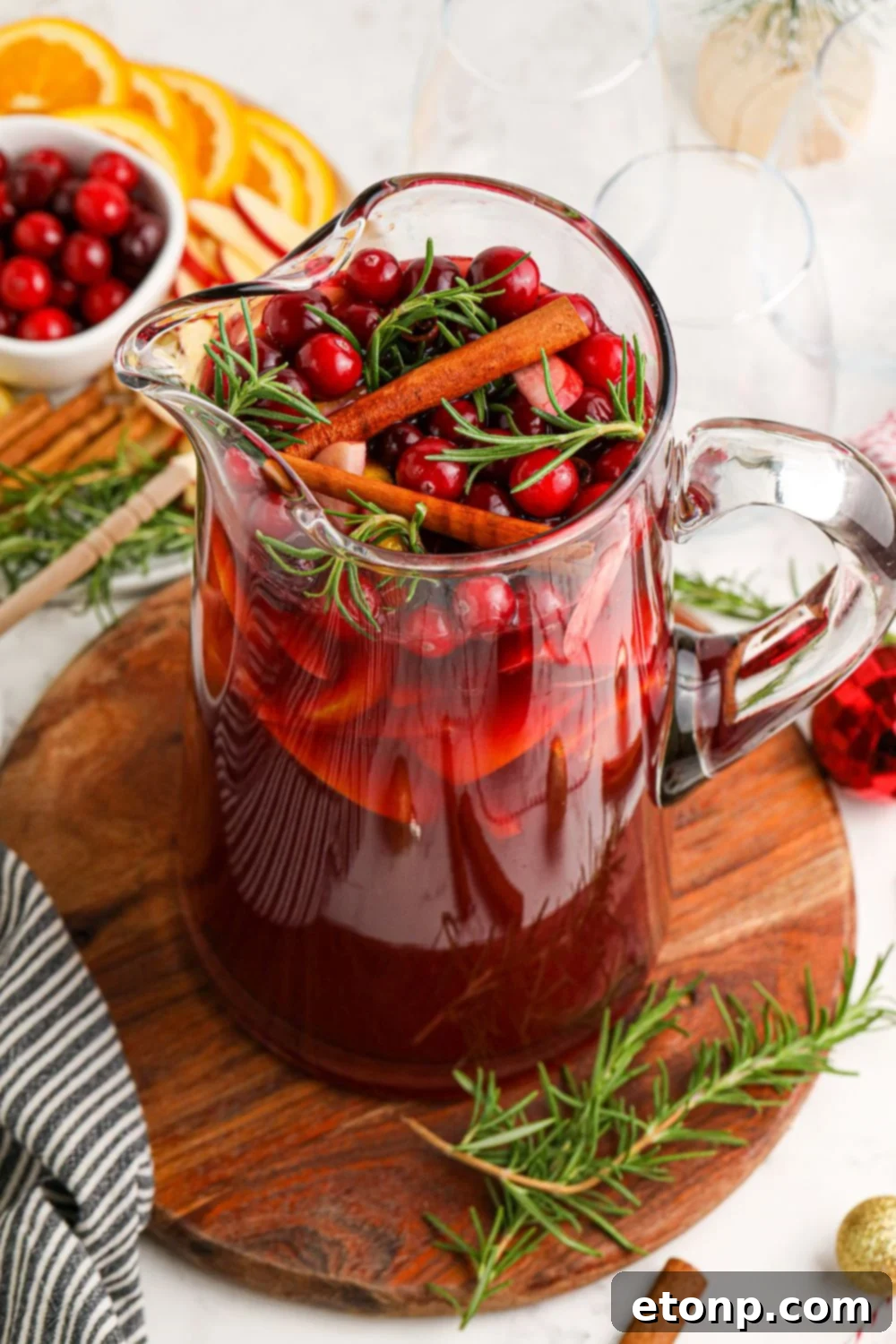 pitcher of sangria topped with cranberries, herbs and cinnamon sticks 