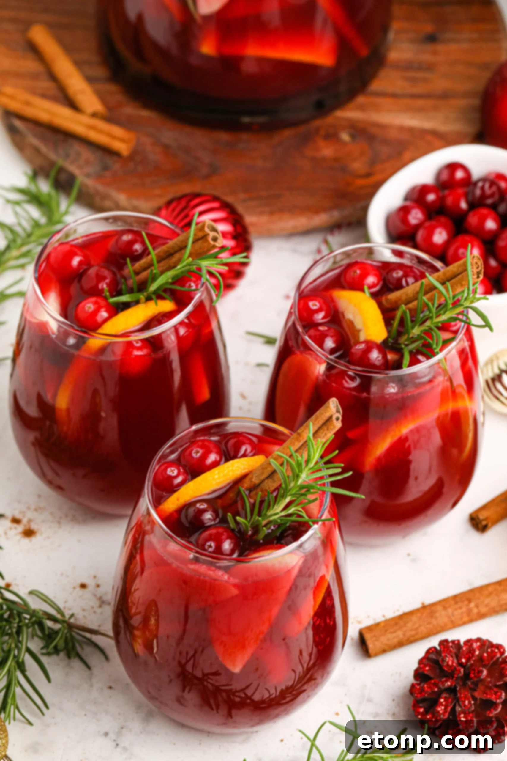 three glasses of Cranberry Apple Christmas Sangria with fresh cranberries and cinnamon sticks in the glasses 