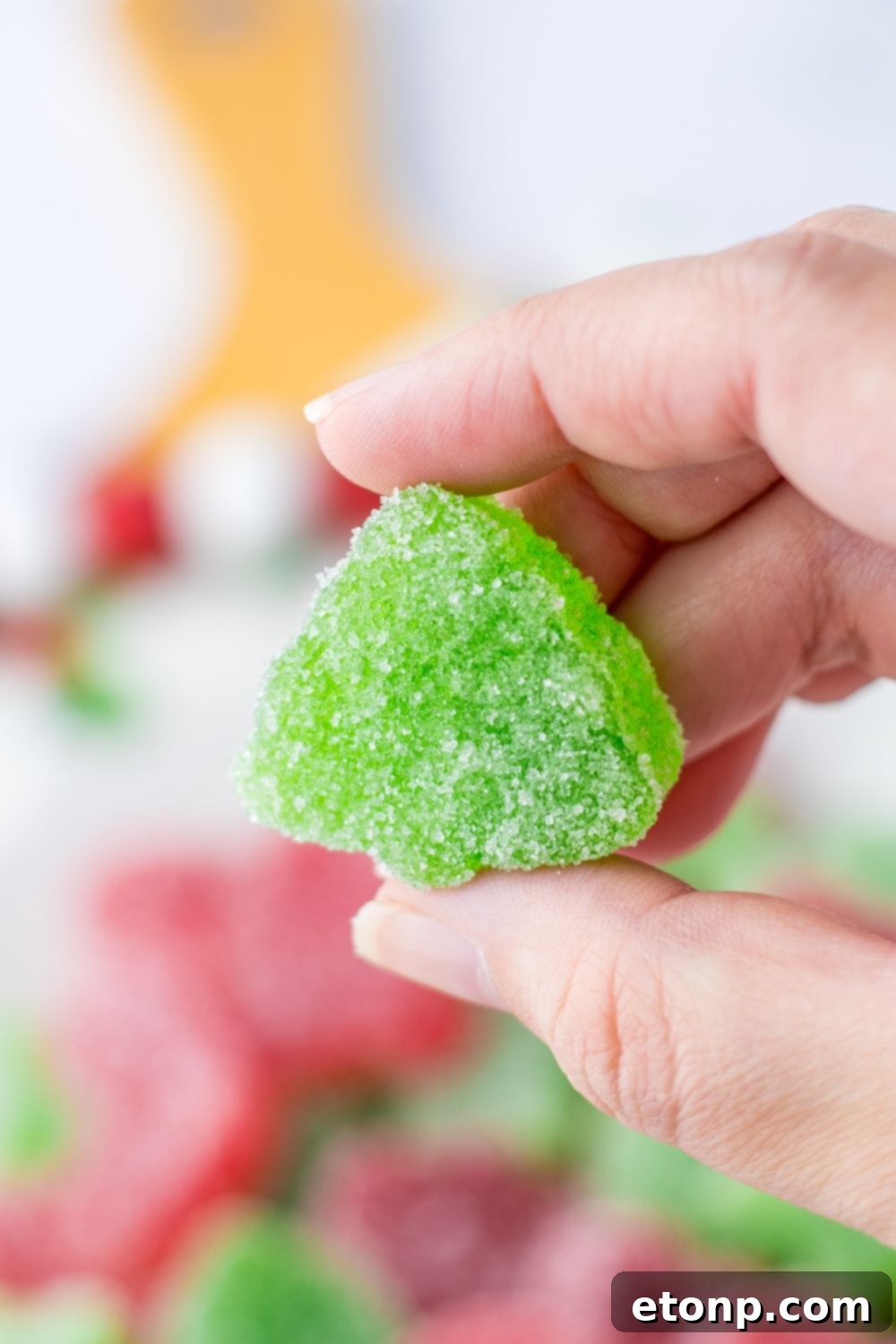 Holiday Gumdrop Gems 18 A hand gently holding a vibrant green gummy candy