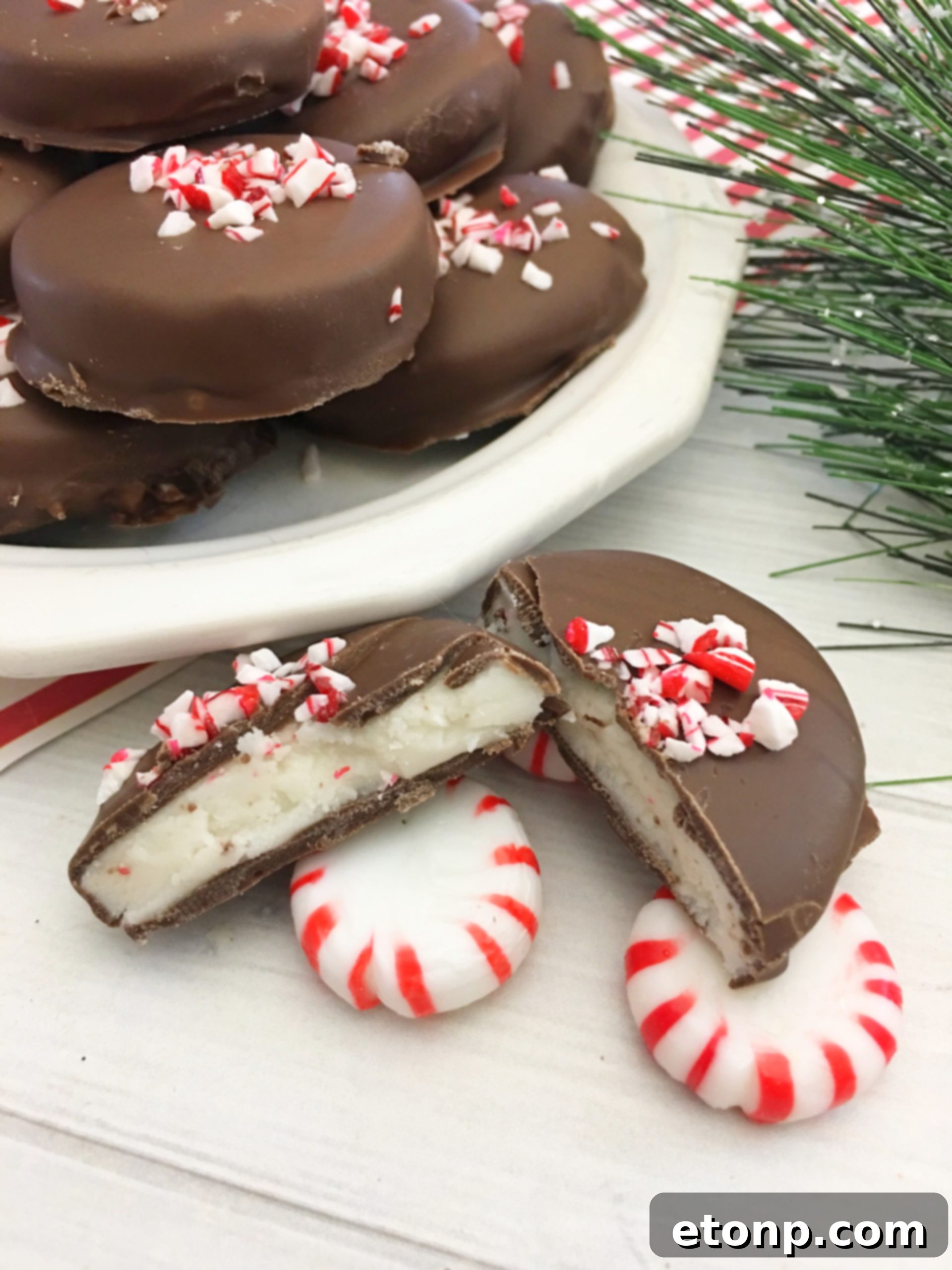 Close-up of a stack of homemade peppermint patties, showing the smooth chocolate coating and a hint of the white peppermint filling inside.